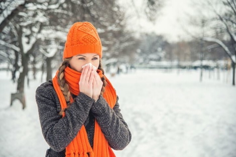 woman blowing her nose in snowy weather