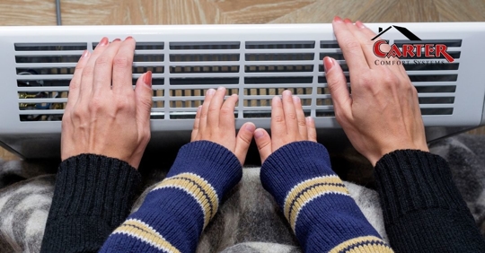 Two people placing their hands in front of a vent.