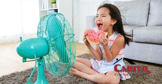 A young girl sitting in front of a fan on a hot day.