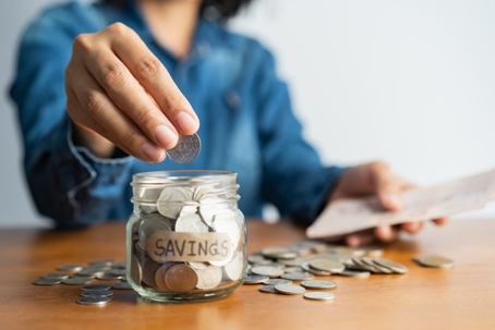 Woman putting coins into a jar.
